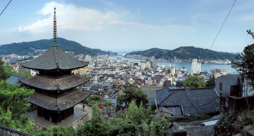 Looking down at a seaside town. A three story pagoda sits in the foreground.