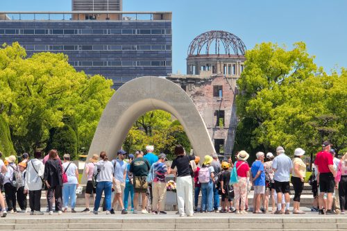 A crowd of tourists around the cenotaph in the middle of a sunny day 