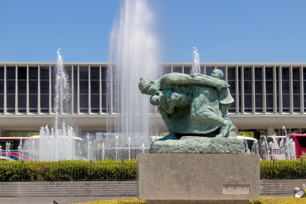 A bronze statue of a woman sheltering children in front of a fountain