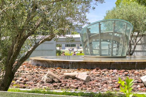 Tourists take a photo of a glass fountain monument