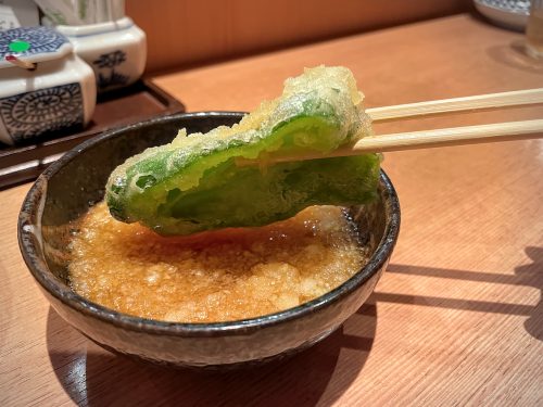 The green flesh of half a green pepper shining through the tempura batter