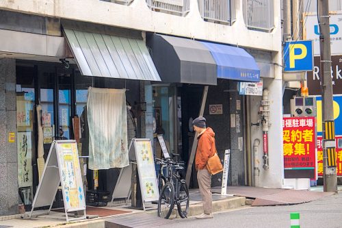 A man looks at a menu in front of Soba Bar Shirakawa