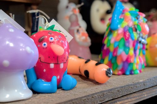 Brilliantly-colored, wax characters with wicks: a goofy looking strawberry is in focus.