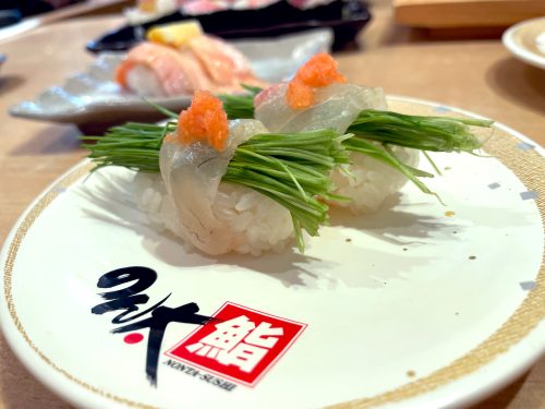Two ornate makizushi with green vegetables and an orange topping at Nonta Sushi in Hiroshima City