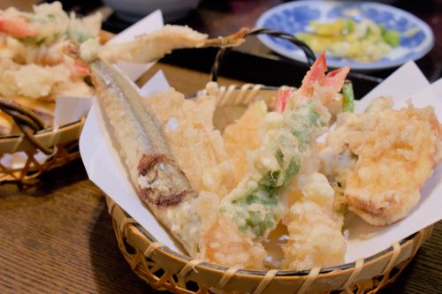 A basket of tempura including a shrimp tempura wrapped in shiso