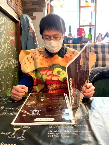 Joy in Hiroshima editor, Kevin Peng looks through the menu while wearing a burger poncho