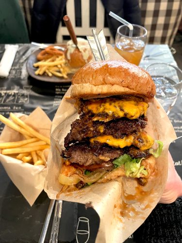 A hand holds up an 18 cm tall hamburger.