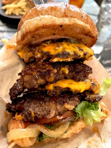 Close up of the many layers of meat, cheese and toppings on a tower burger