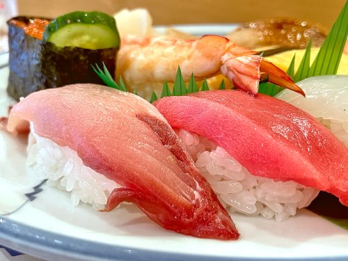 A close up of pink yellowtail and bright red tuna nigiri sushi