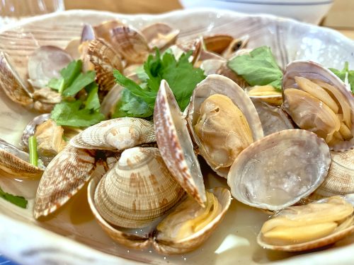 A close up of steamed clams in a bowl garnished with parsley
