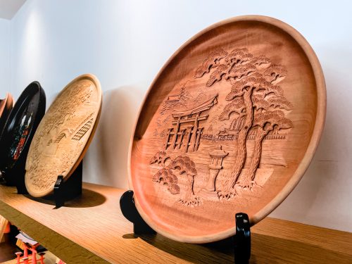 A wooden tray with a sculpture of Miyajima's Great Torii and landscape emerging from the wood