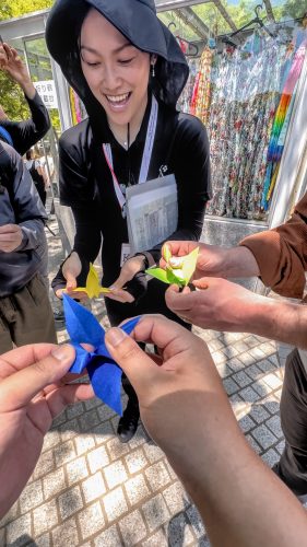 A woman guides a group folding paper cranes