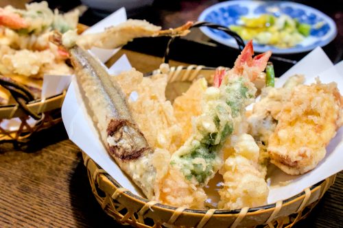A basket of tempura including a shrimp tempura wrapped in shiso