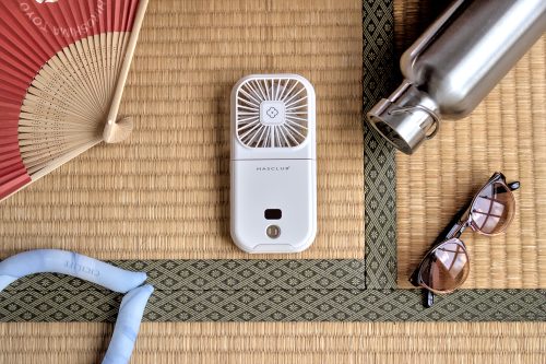A square-shaped electric hand fan laid on a tatami mat