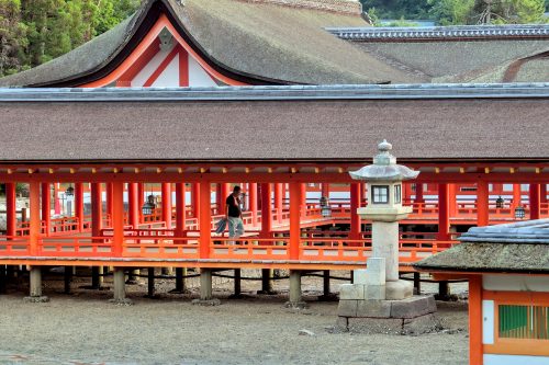 A man walks down an open air corridor in a Shinto temple complex