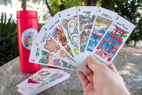 A hand holds up a spread of playing cards. Each card is decorated differently.